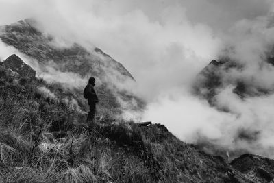 Man standing on mountain against cloudy sky
