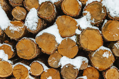 The cut tree trunks are put together and covered with snow. background image