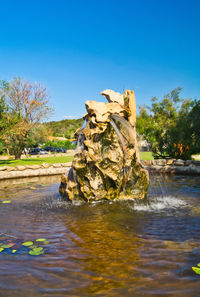 Scenic view of rock formation amidst trees against clear blue sky