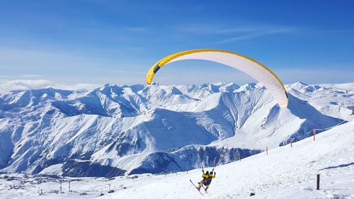 Person skiing on snowcapped mountains against sky