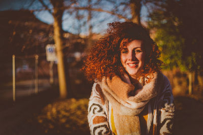 Portrait of smiling young woman standing against trees