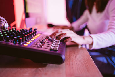 Close up producer woman hands nearby soundboard is mixing, adjusting and editing sounds.