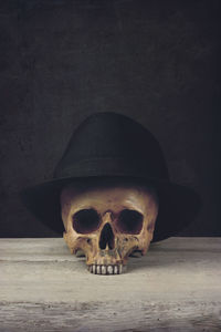 Close-up of human skull wearing hat against wall