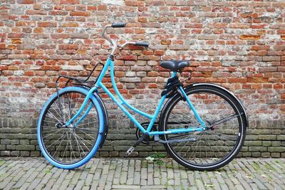 Blue bicycle parked against wall