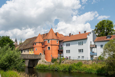 Houses by river and buildings against sky