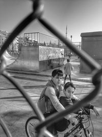 Boys riding on bicycle on road against sky