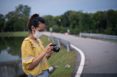 Series photo of young women wearing surgical protection mask playing with camera in the evening