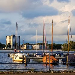 Boats moored at harbor against cloudy sky