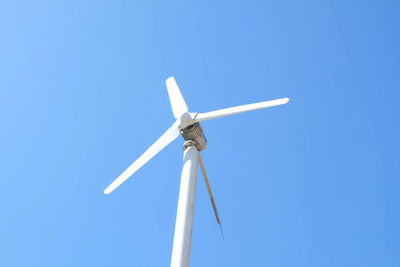 Low angle view of wind turbine against clear blue sky