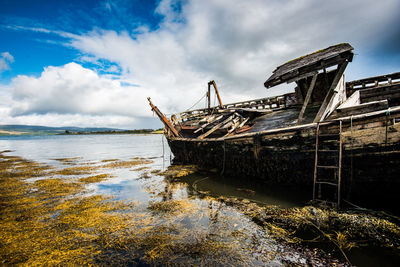 Abandoned ship moored on sea against sky