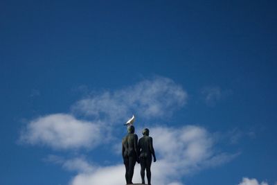 Low angle view of birds against blue sky