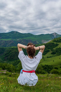 Rear view of woman with arms raised against sky