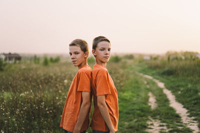 Funny twin brother boys playing outdoors on field at sunset.