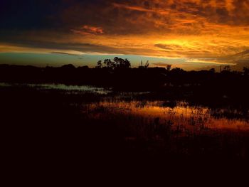 Scenic view of silhouette landscape against dramatic sky during sunset