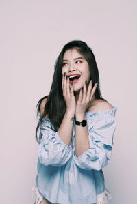 Beautiful young woman standing against white background
