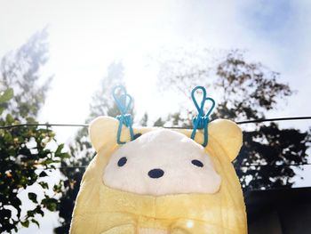 Close-up of stuffed toy hanging on tree against sky