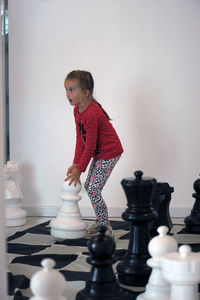 Girl standing on artificial chess board at home