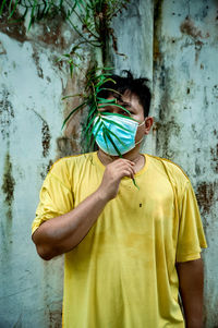 Full length of young man standing against yellow wall