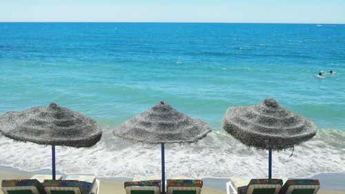 View of beach umbrella near sea water against clear sky