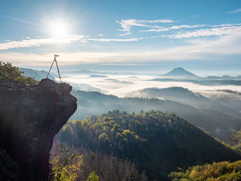 Camera stand on tripod photographing mountain, blue sky and foggy landscape. mountains background