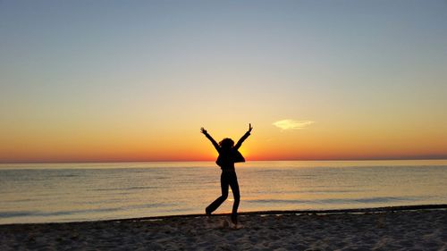 Silhouette of people on beach at sunset
