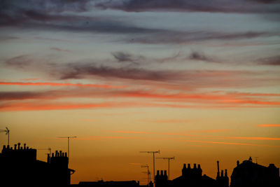 Silhouette buildings against dramatic sky during sunset