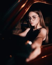 Young woman sitting in car at night