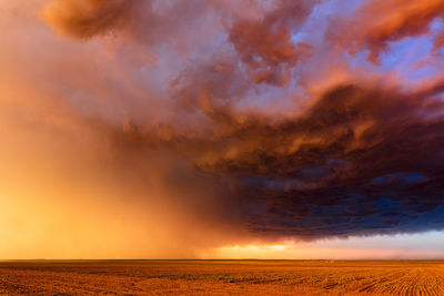 Sunset light illuminates dramatic storm clouds over a farm field in colorado.