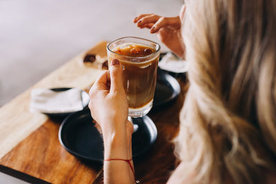 Midsection of woman holding drink on table