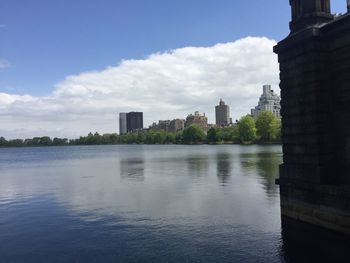 City at waterfront against cloudy sky