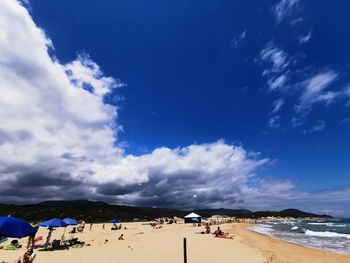 Group of people on beach against blue sky