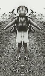Rear view of woman with arms outstretched standing on field