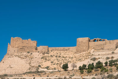 Low angle view of fort against clear blue sky