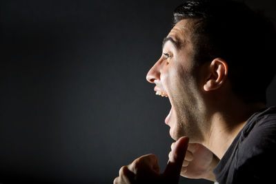 Portrait of young man looking away against black background