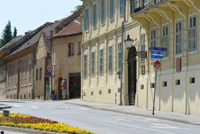 Road by buildings against sky in city