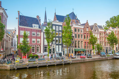 Canal by buildings against sky in city