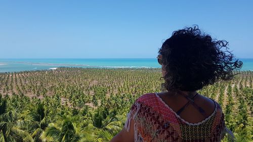 Woman by sea against clear sky