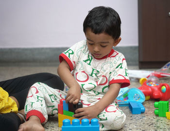 Cute boy playing with toy while sitting at home