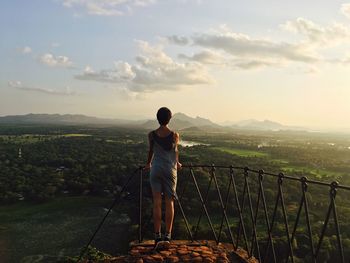 Full length rear view of woman standing at observation point against sky