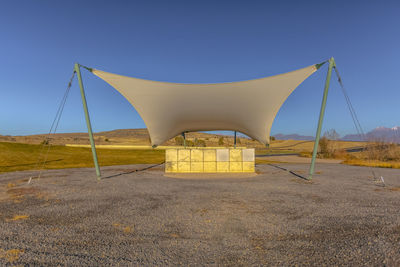 Built structure on field against clear blue sky