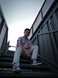 Portrait of young man sitting against clear sky