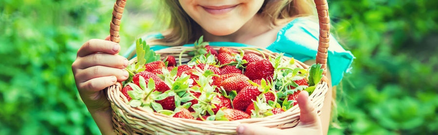 Cute girl holding basket of strawberries