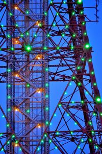 Illuminated television tower against blue sky