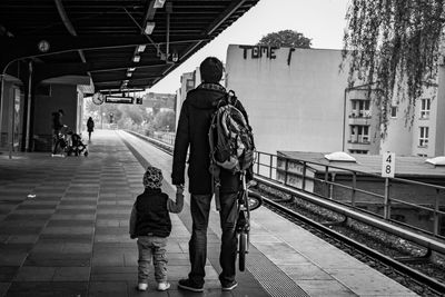 Rear view of father and son standing on railroad station platform