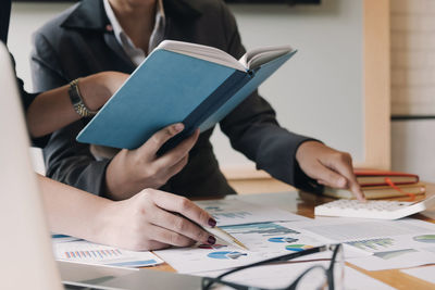 Midsection of woman reading book on table