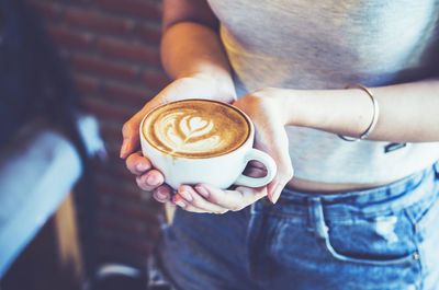 Midsection of woman holding coffee cup