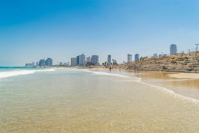 City buildings by sea against clear sky