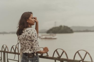 Woman standing by railing against sky