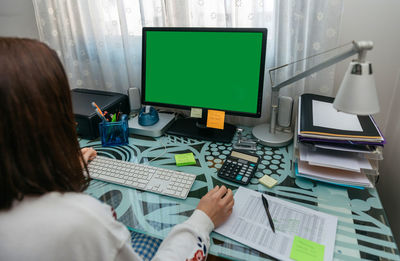 Rear view of man and woman using laptop on table