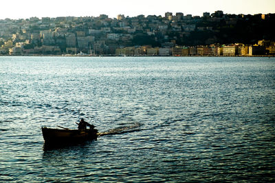 Man sailing on sea against sky in city